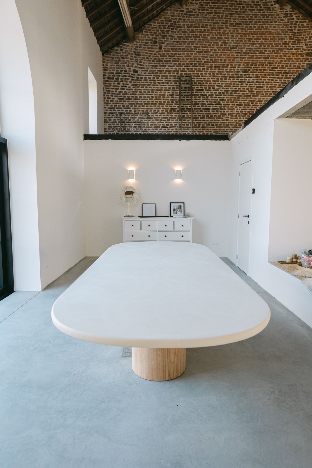Grande table ovale en Mortex® fabriquée en Belgique, dans un loft aux murs de brique
