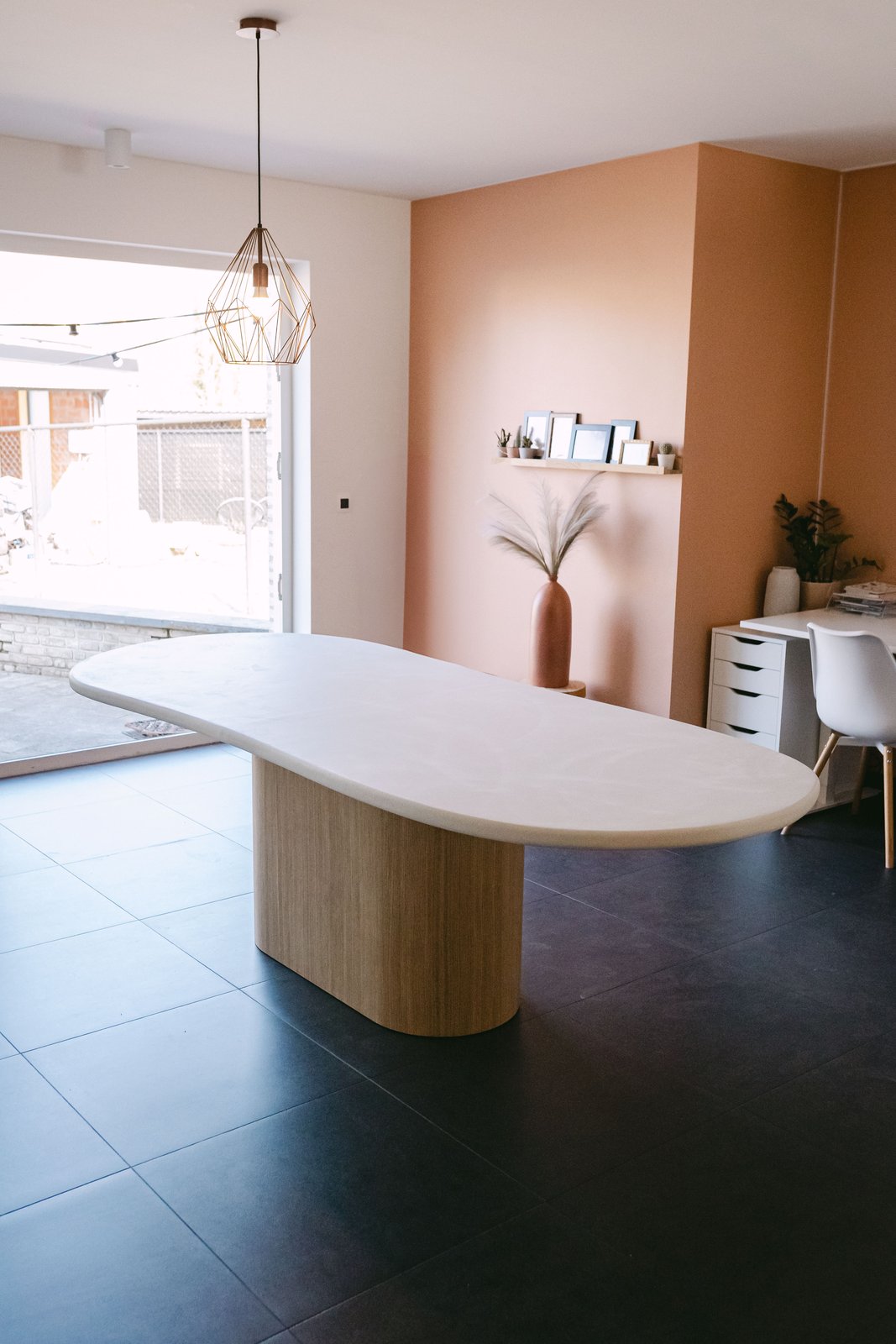 Table à manger en Mortex® sur mesure devant un mur terracotta, piètement chêne