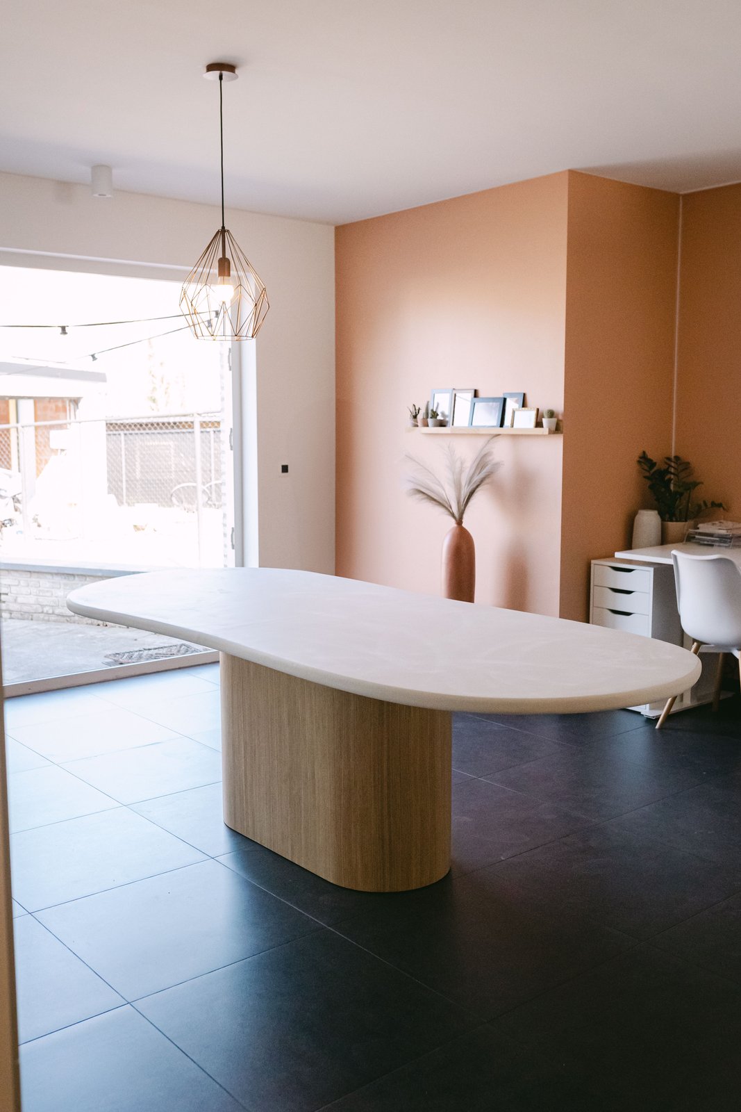 Table ovale en Mortex® teinte Lin dans une salle à manger aux murs terracotta